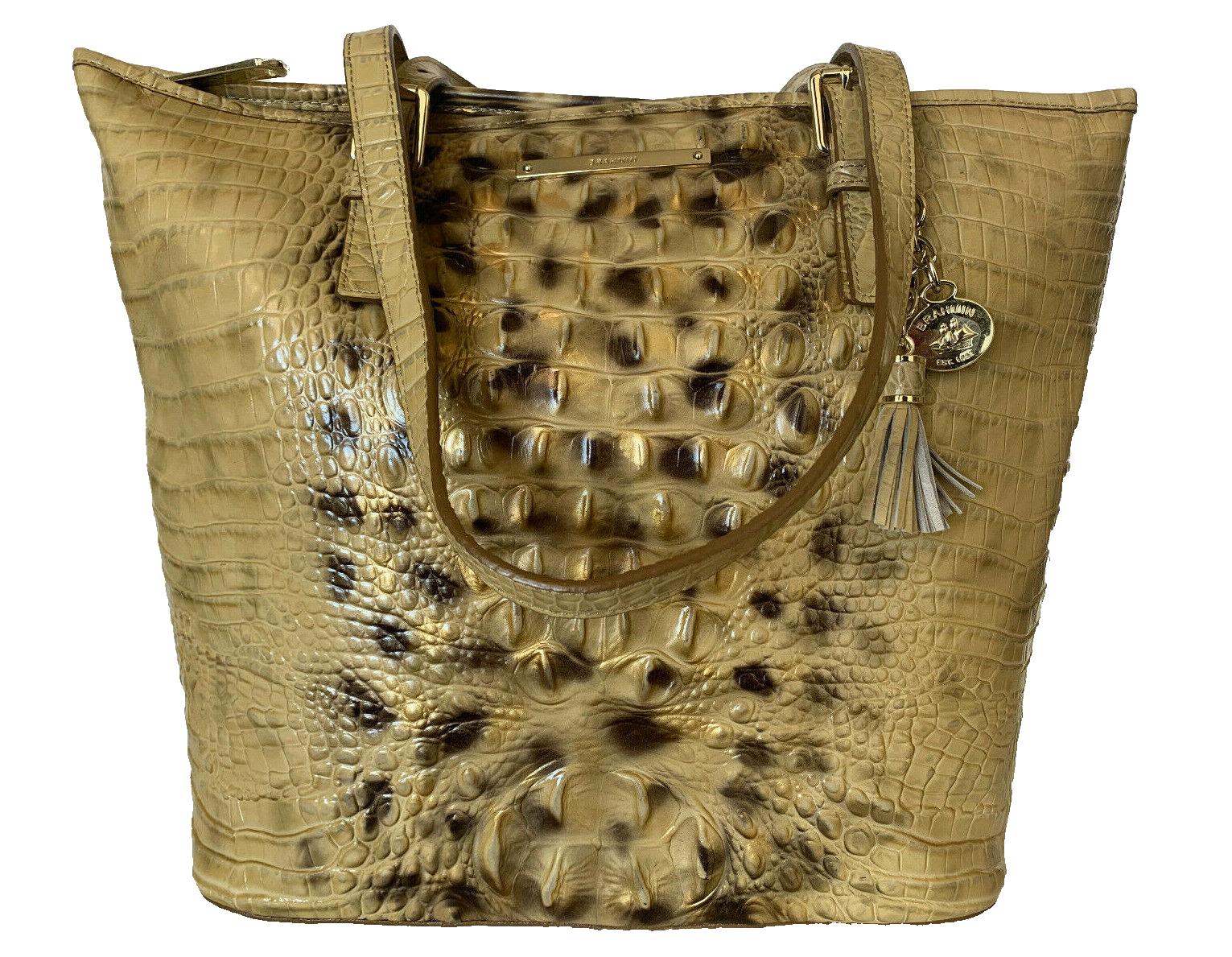 Gold crocodile-patterned leather handbag with tassel.